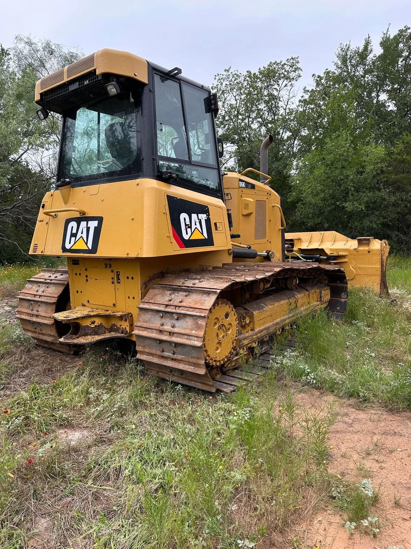 Yellow Caterpillar D6K track dozer with blade attachment on cleared site