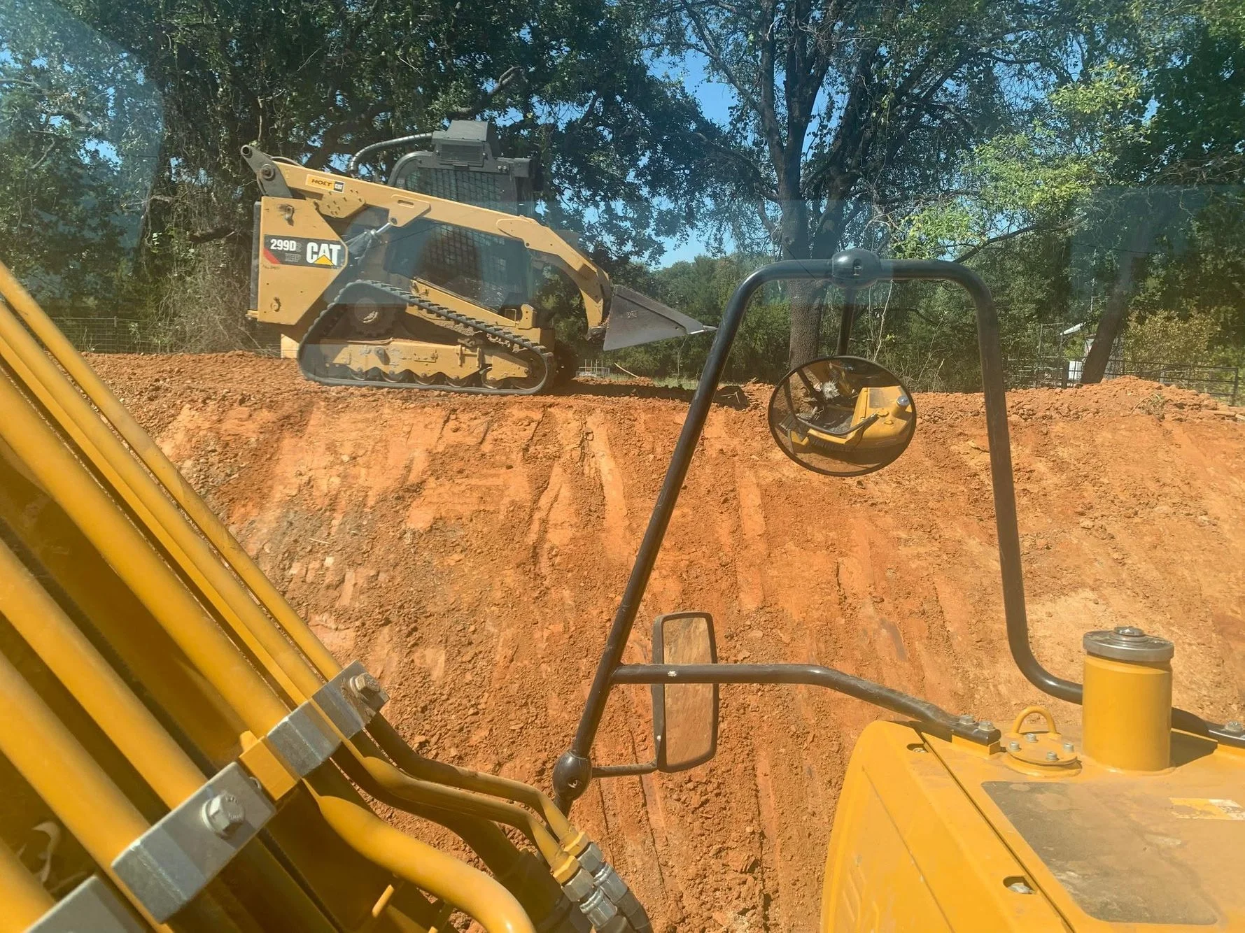 CAT 289D compact track loader grading red clay soil on residential excavation site