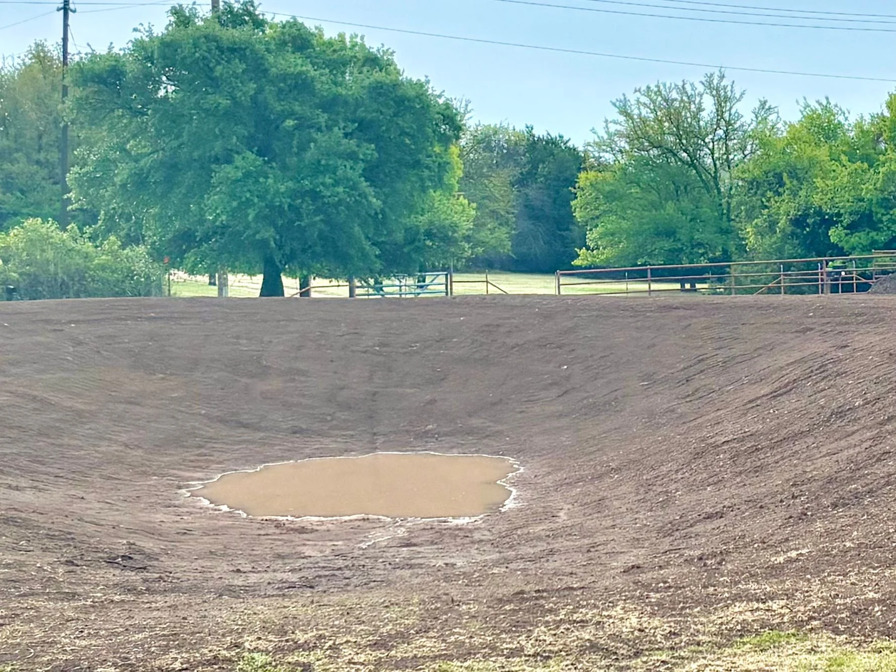 Excavated drainage pond with compacted soil berms and standing water in rural setting