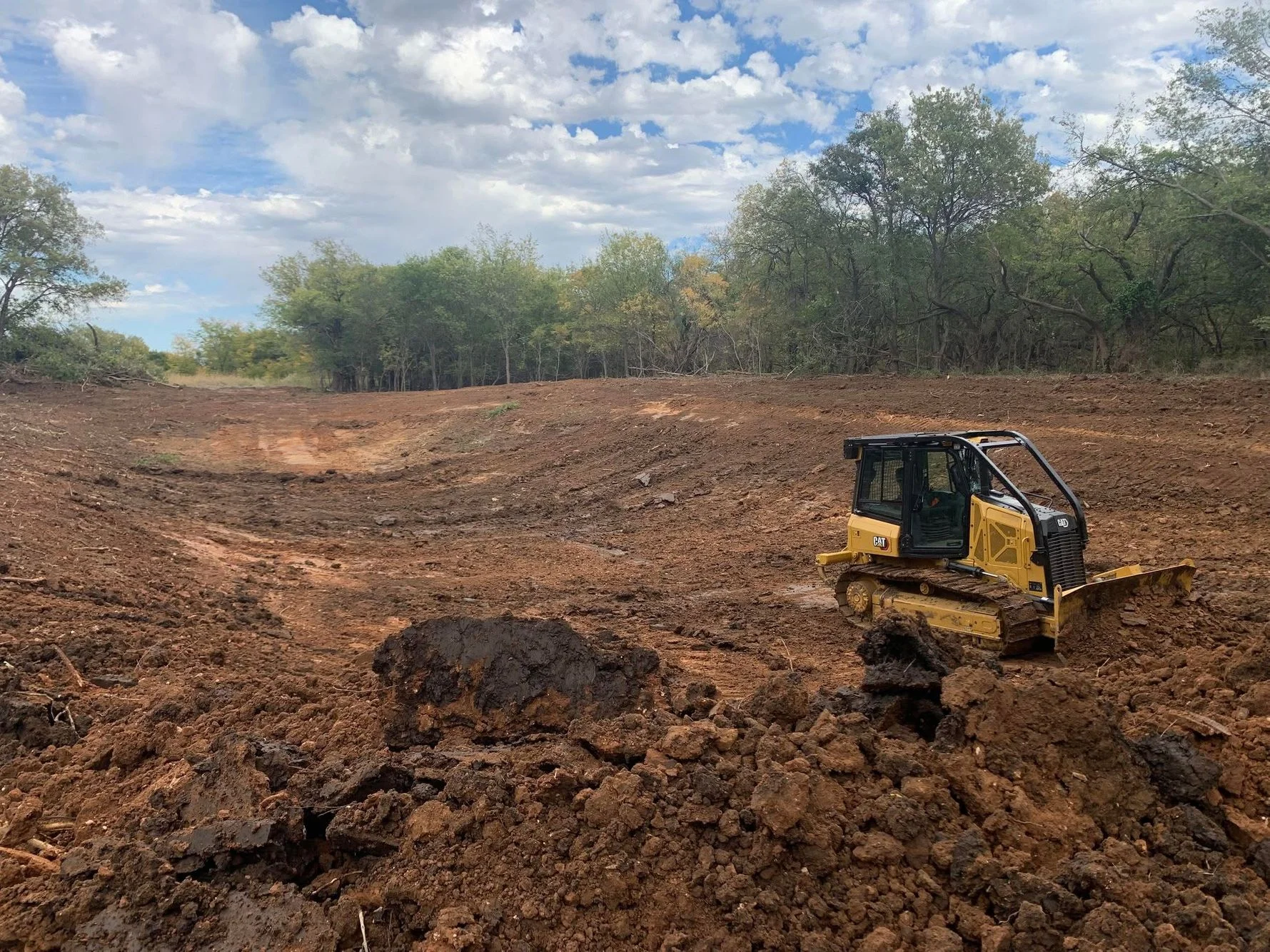 CAT track dozer clearing wooded land with rock removal and grading work