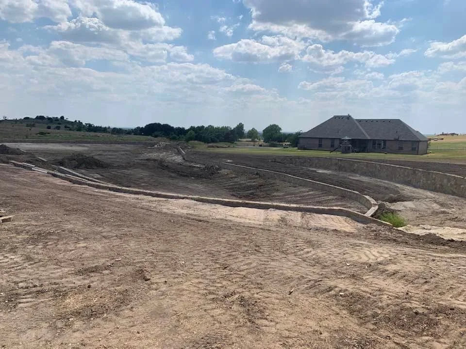 Excavated pond basin with sloped earthwork and compacted soil grading on rural property